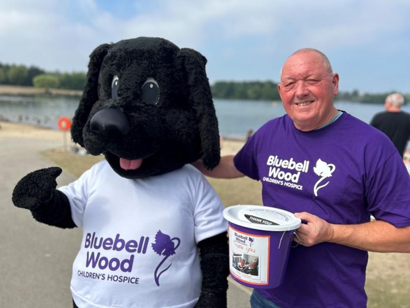 A man fundraising next to a black mascot dog