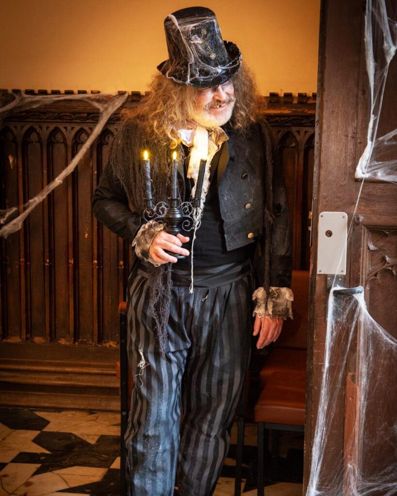 A man dressed up as a ghostly figure holding a candle stick