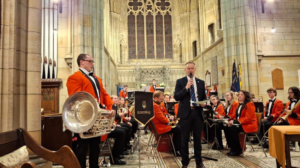 A band of musician wearing their red livery with instruments sat in a church